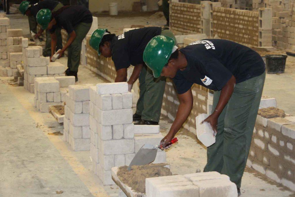 Workers building masonry walls indoors